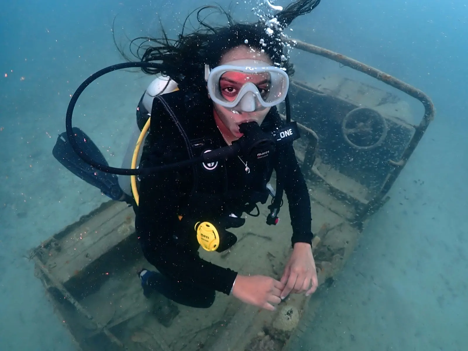 Diver hovering above a jeep wreck on a sandy seabed during SSI Wreck Specialty training